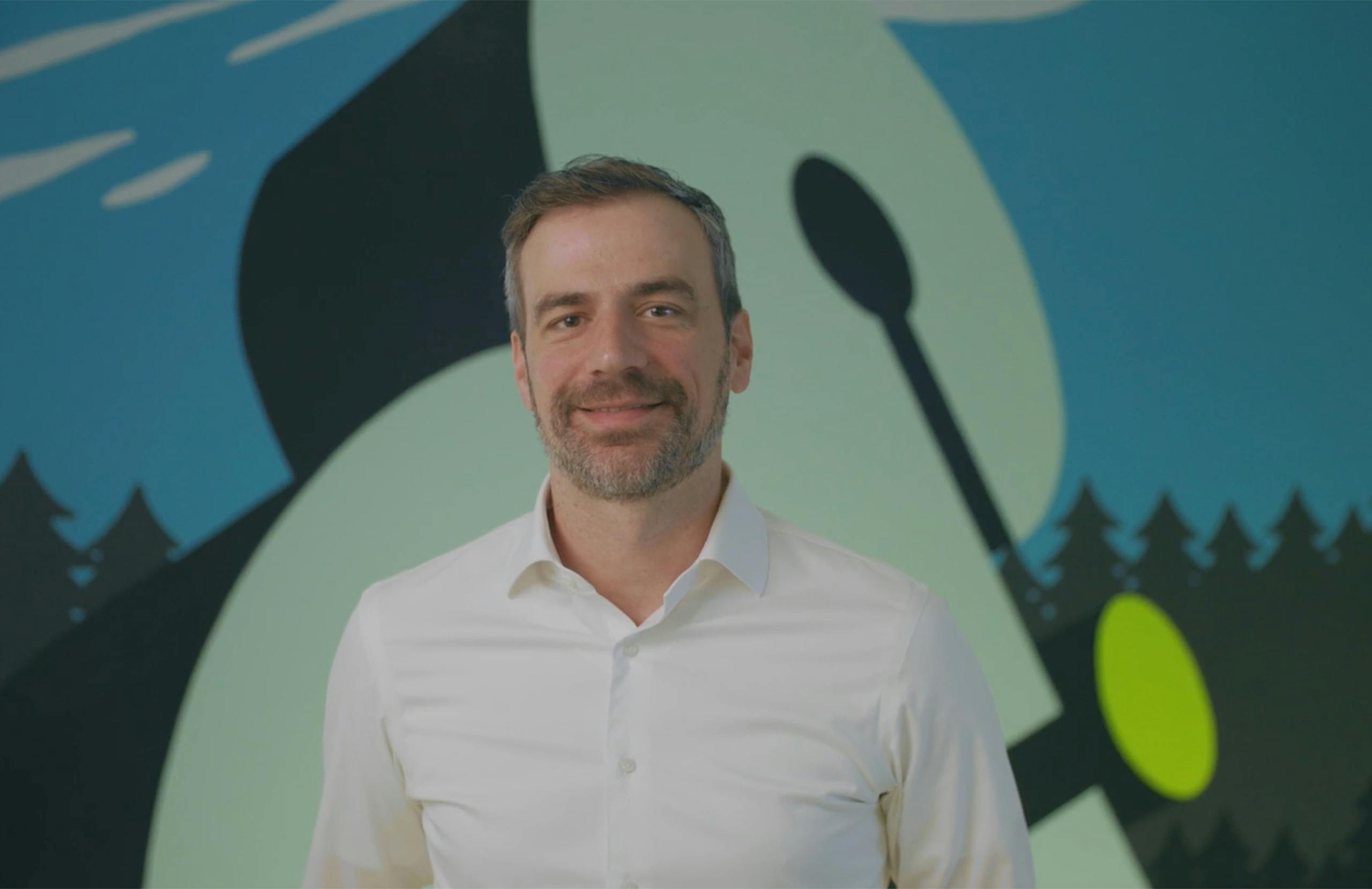 Derek Slager standing against a mural of Amperity logo