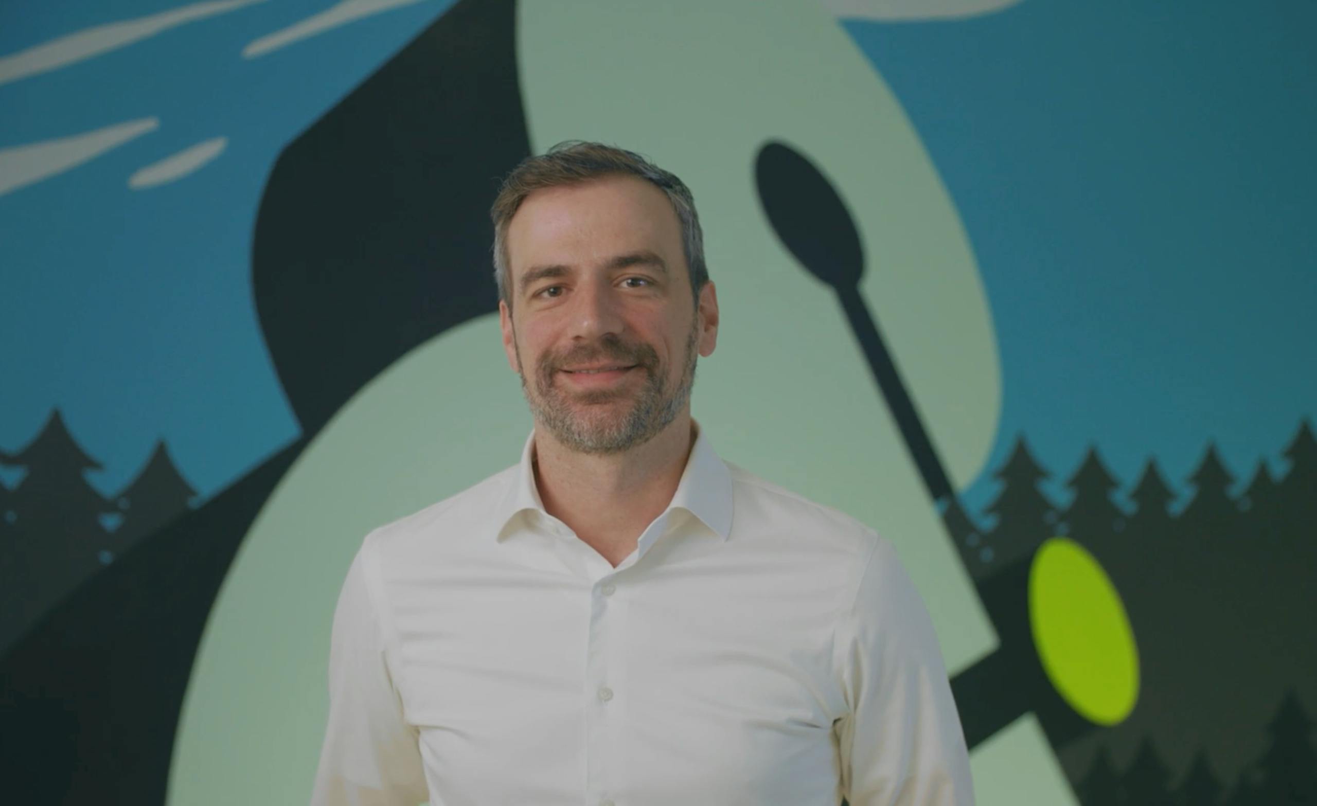 Derek Slager standing against a wall with the Amperity logo