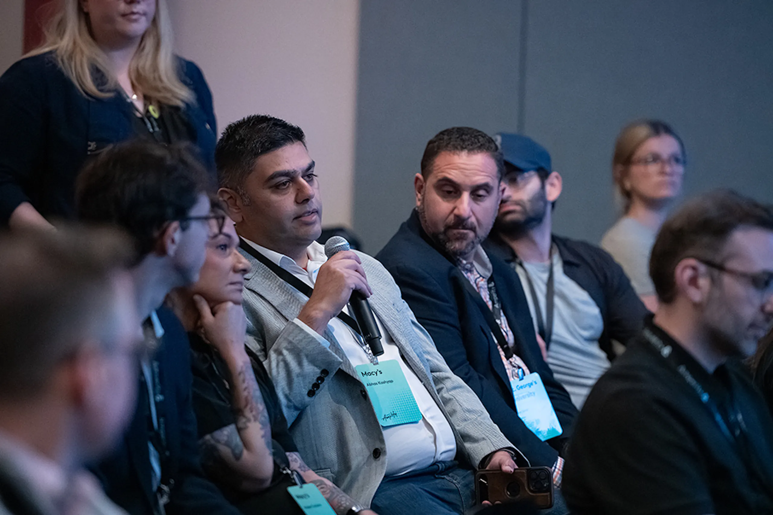A man holding a microphone in the audience at Amplify 2026.