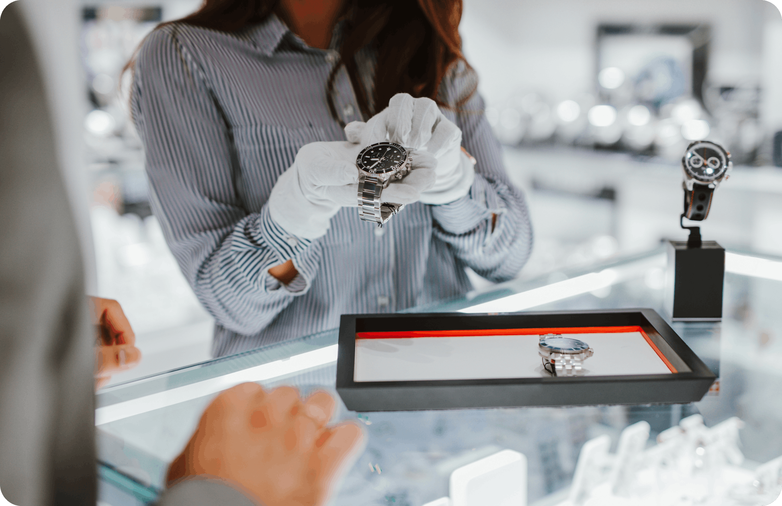 Sales attendant wearing white gloves shows customer a watch out of a display case