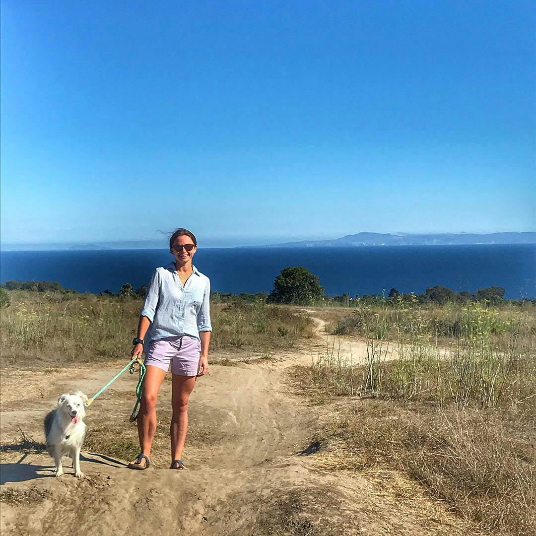 Jack's hiking partners, a woman with a dog on a leash by the water