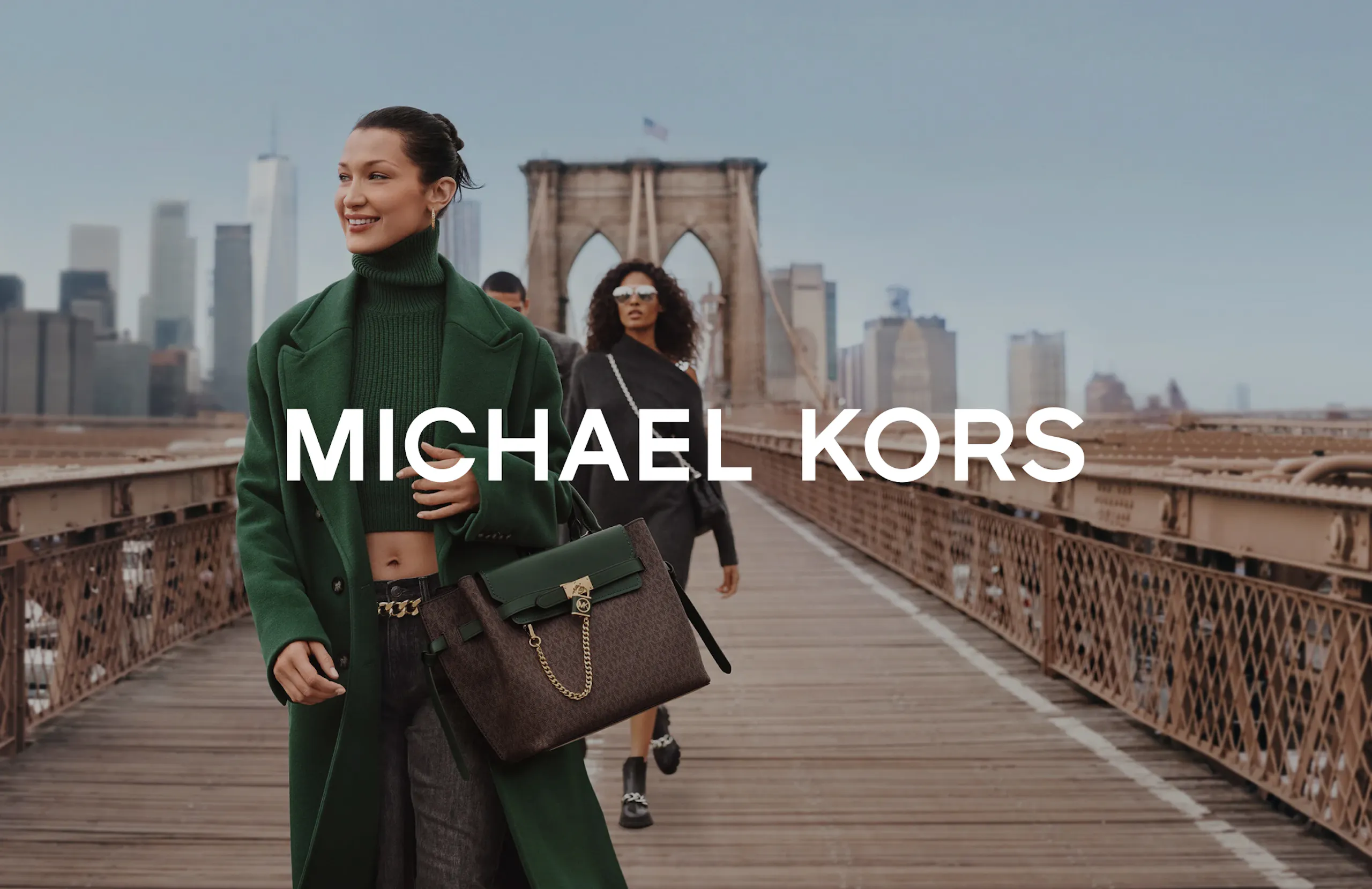 Model crosses Brooklyn Bridge holding a handbag