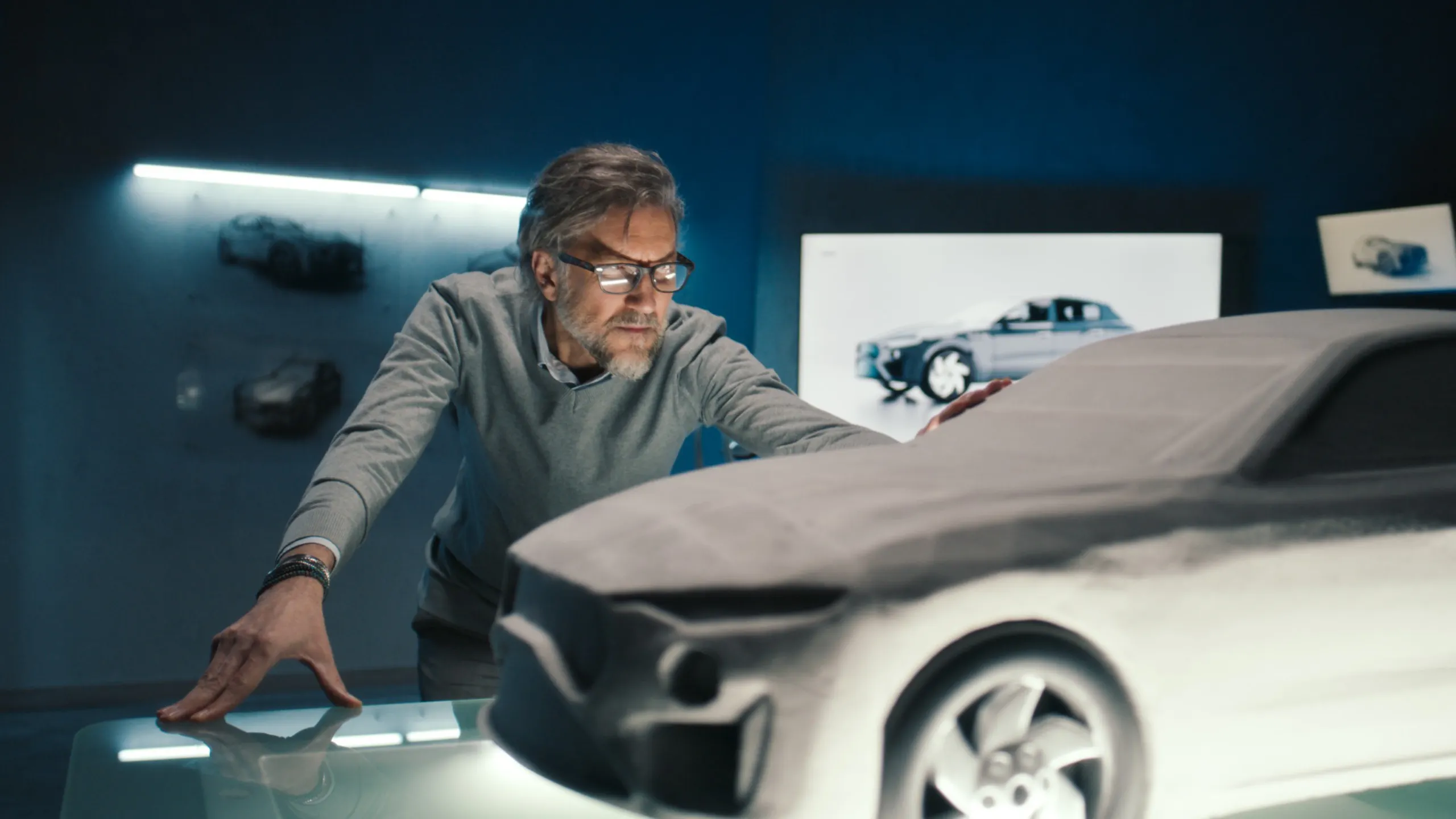 Designer examining a clay car model in an automotive studio.