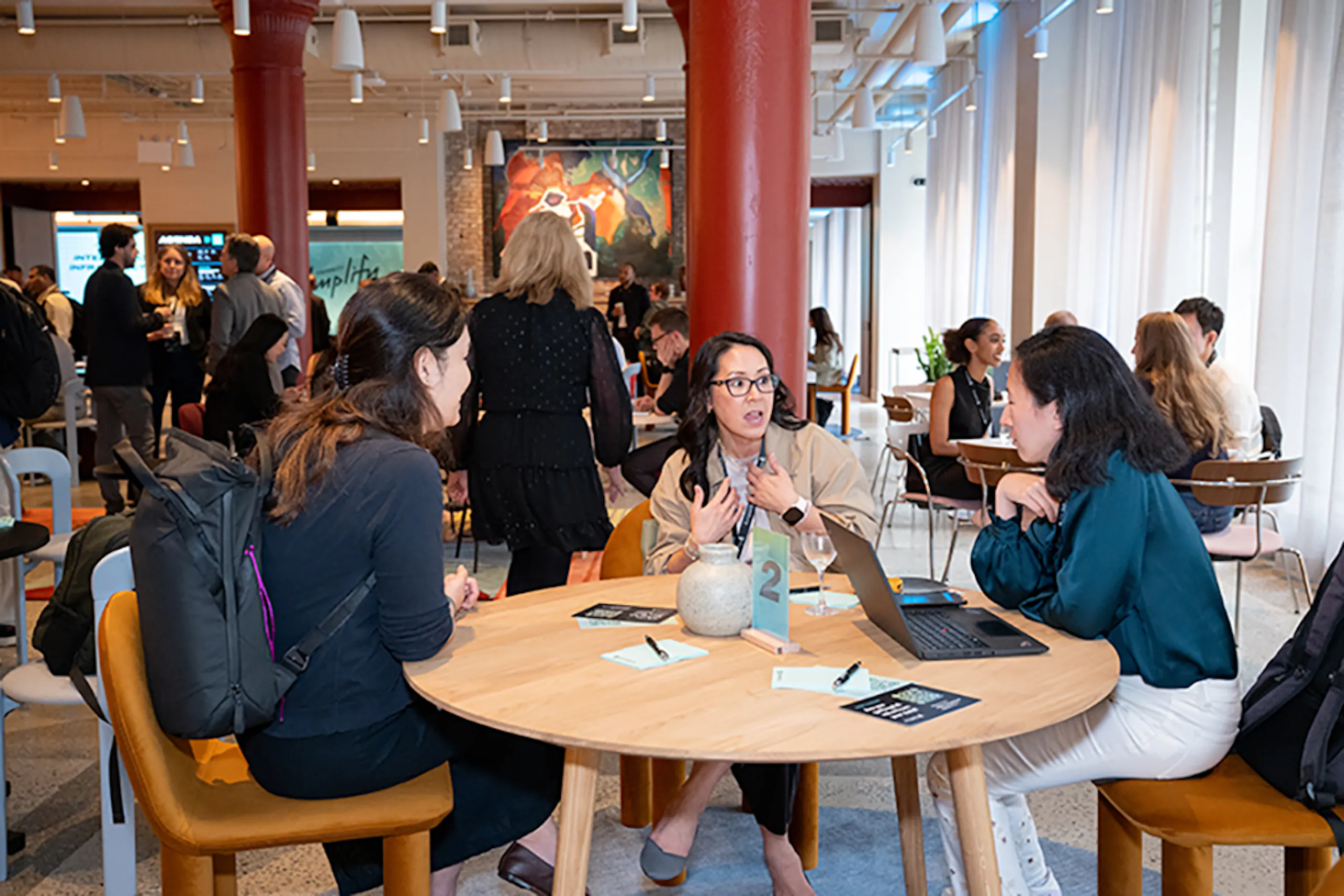 Three women seated at a table in discussion at Amplify 2026.