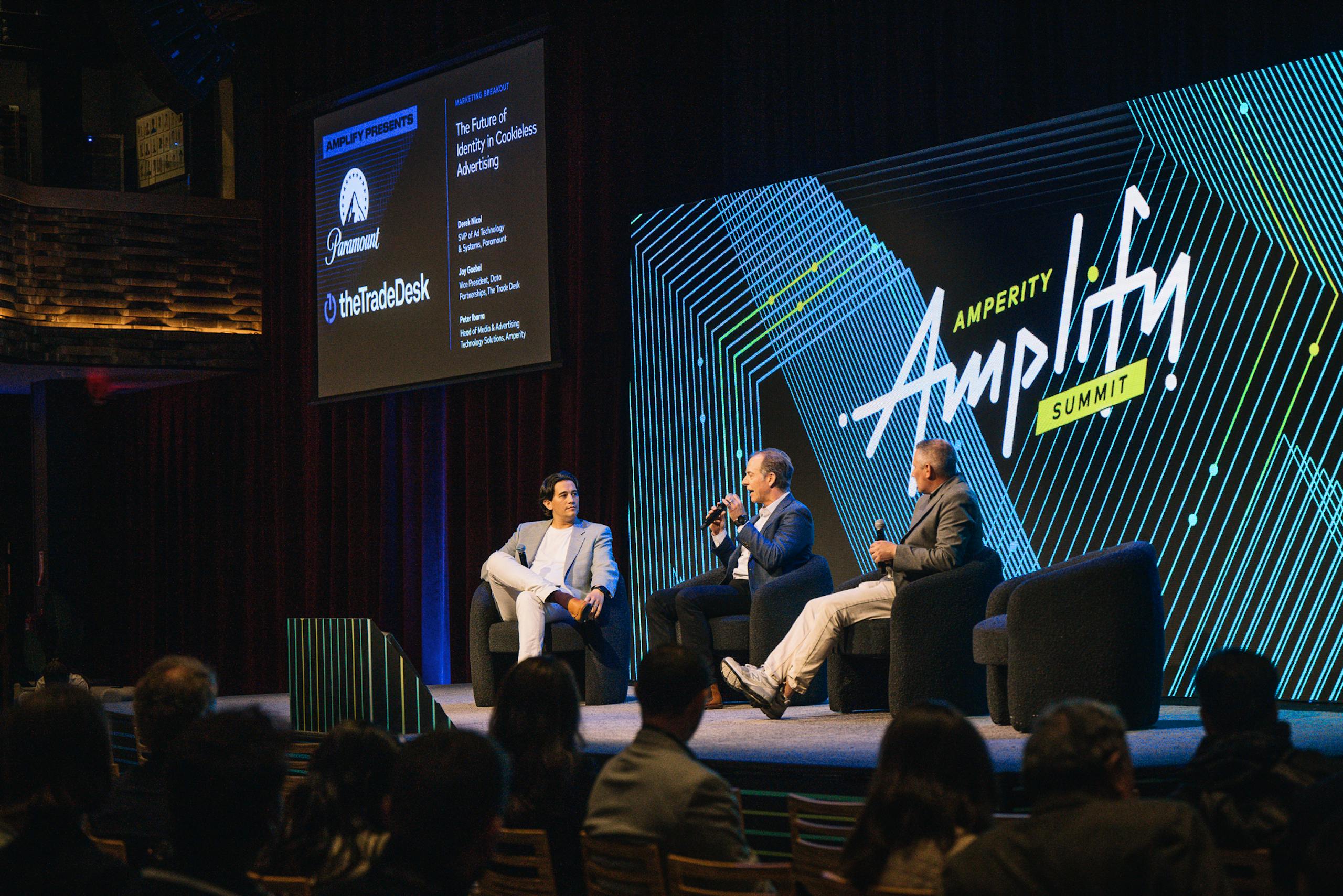 Three people sitting on stage at Amplify, Amperity's annual summit, discussing the customer data space. 